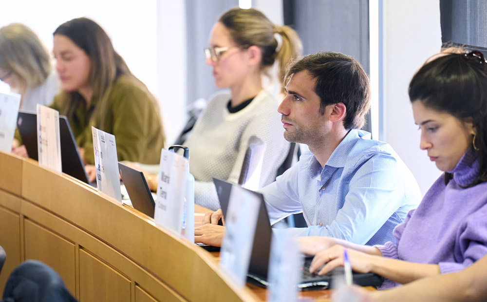 La imagen muestra a varios profesionales trabajando con ordenadores portátiles en un aula de formación ejecutiva, siguiendo atentamente una sesión centrada en el análisis y la toma de decisiones.