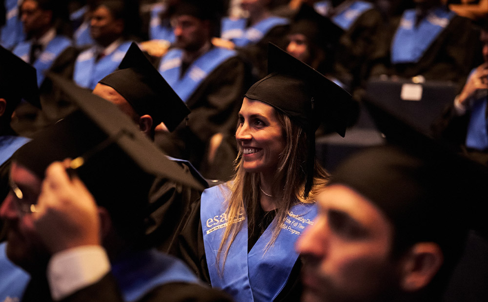 The image depicts a graduation ceremony where participants are wearing academic gowns and caps while celebrating the completion of their studies. This scene represents academic achievement and professional development through postgraduate education.