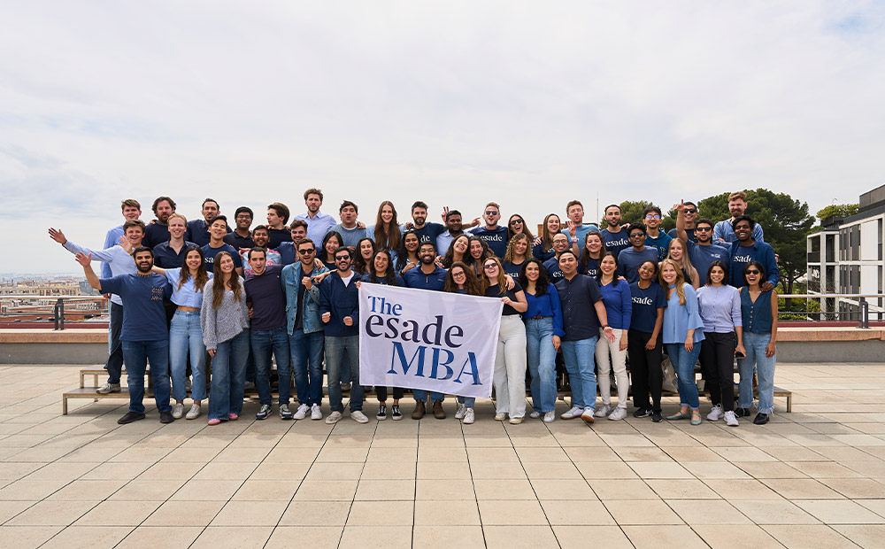 The image shows a large group of MBA participants gathered outdoors during a community activity.