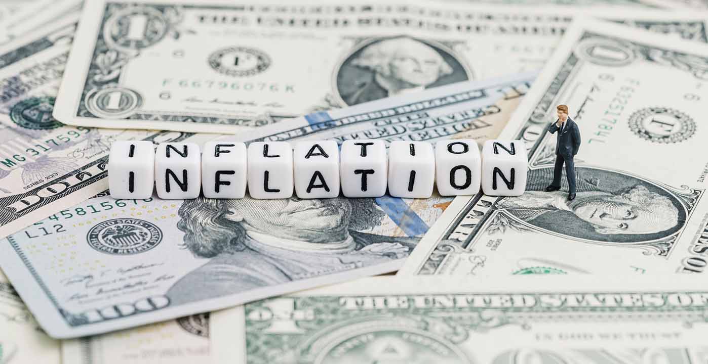 Cubes spelling the word 'inflation' on top of a pile of dollar bills