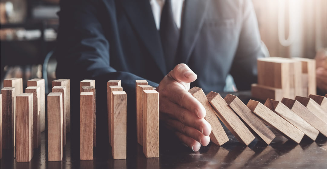 Mano que para la caida de unas piezas de un efecto dominó