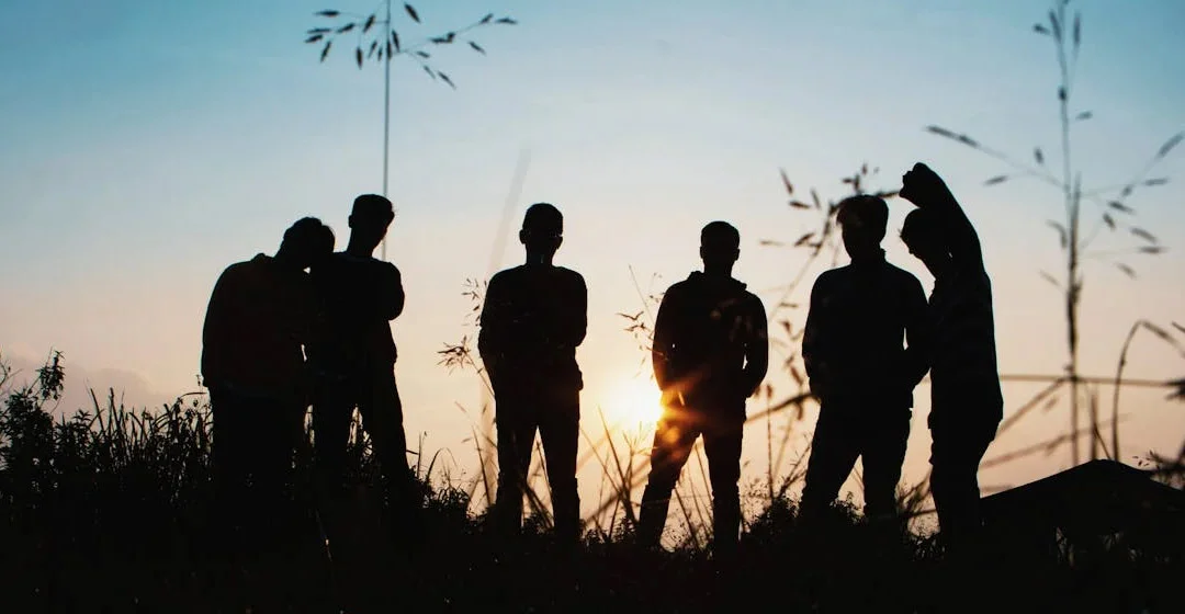 silueta grupo de personas de pie sobre el campo de hierba