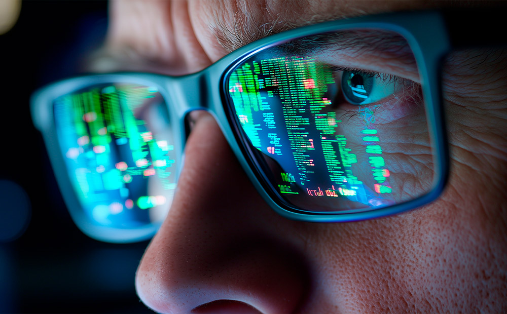 Primer plano de una persona con gafas, donde se reflejan en los cristales líneas de código y gráficos brillantes, simbolizando el dominio de herramientas digitales y el análisis de datos. Esta representación visual destaca habilidades clave para convertirse en director de marketing, como la capacidad técnica, el pensamiento analítico y el conocimiento profundo de estrategias SEO, fundamentales para liderar equipos y tomar decisiones basadas en métricas reales.