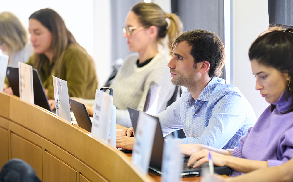 Vemos un grupo de personas en un aula, trabajando con ordenadores portátiles y documentos, lo que refleja un entorno de formación y análisis.